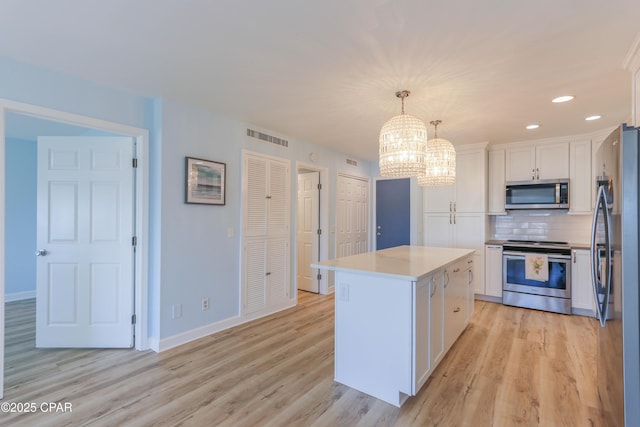 kitchen with stainless steel appliances, a notable chandelier, white cabinets, and decorative backsplash