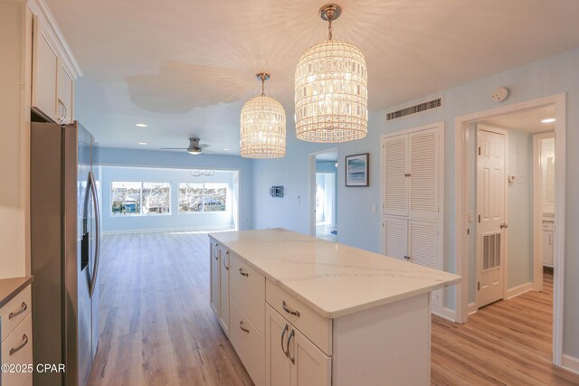 kitchen featuring white cabinetry, stainless steel fridge with ice dispenser, visible vents, and a kitchen island