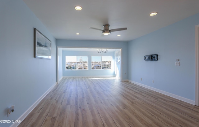 unfurnished room featuring ceiling fan with notable chandelier and light hardwood / wood-style flooring