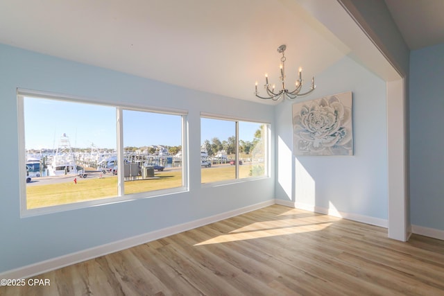 unfurnished room featuring lofted ceiling, hardwood / wood-style flooring, and a chandelier