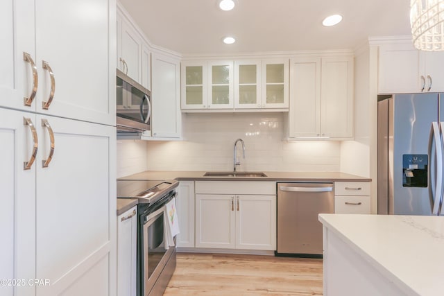 kitchen with white cabinets, tasteful backsplash, appliances with stainless steel finishes, and a sink