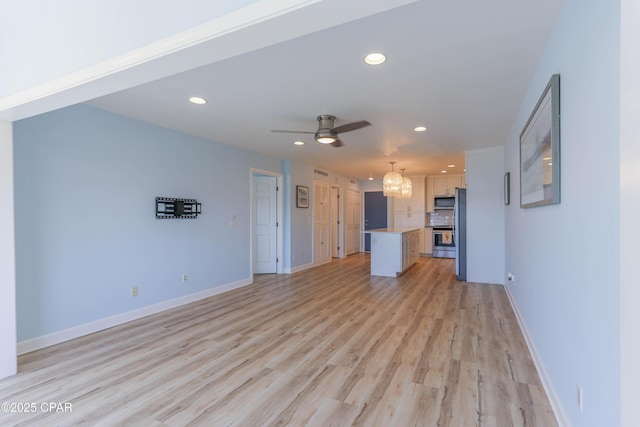 unfurnished living room with ceiling fan with notable chandelier and light hardwood / wood-style floors