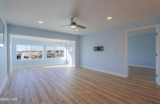 unfurnished room featuring recessed lighting, baseboards, wood finished floors, and ceiling fan with notable chandelier