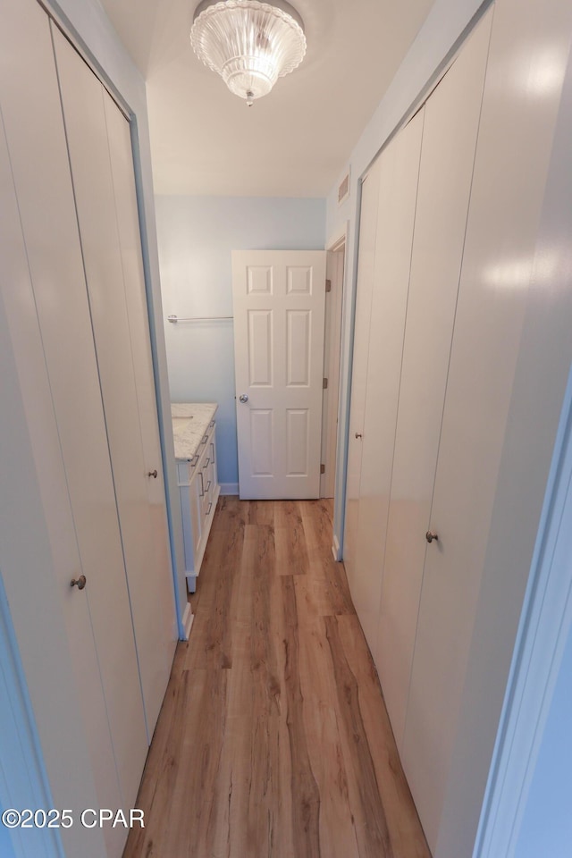 corridor featuring light wood-style flooring and visible vents