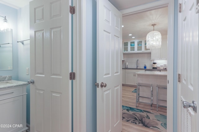 bathroom with wood finished floors, tasteful backsplash, a chandelier, and vanity