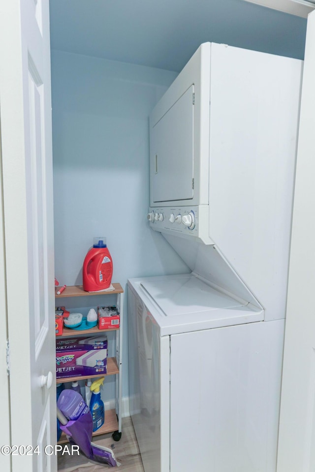 clothes washing area featuring light wood finished floors and stacked washer and clothes dryer