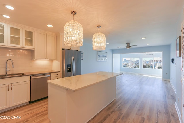 kitchen with sink, white cabinetry, hanging light fixtures, stainless steel appliances, and decorative backsplash