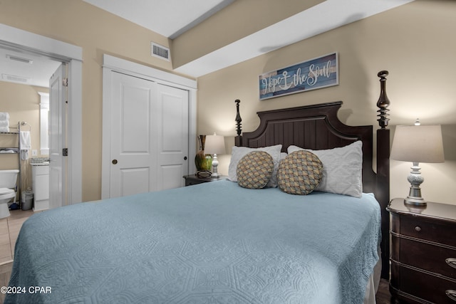 bedroom featuring connected bathroom, a closet, and light tile patterned flooring