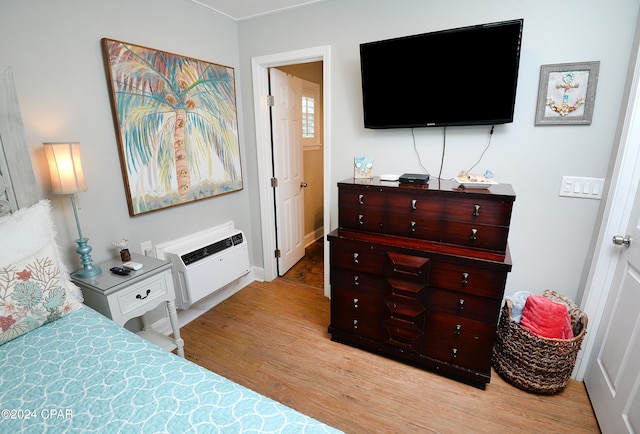 bedroom with a wall mounted air conditioner and light hardwood / wood-style flooring