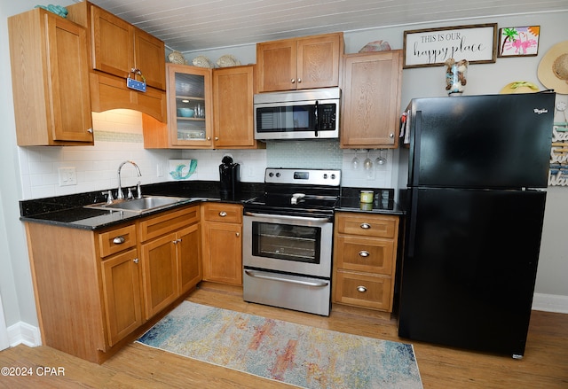 kitchen featuring stainless steel appliances, light hardwood / wood-style floors, sink, and backsplash