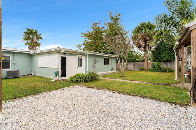 back of property with a lawn and central AC