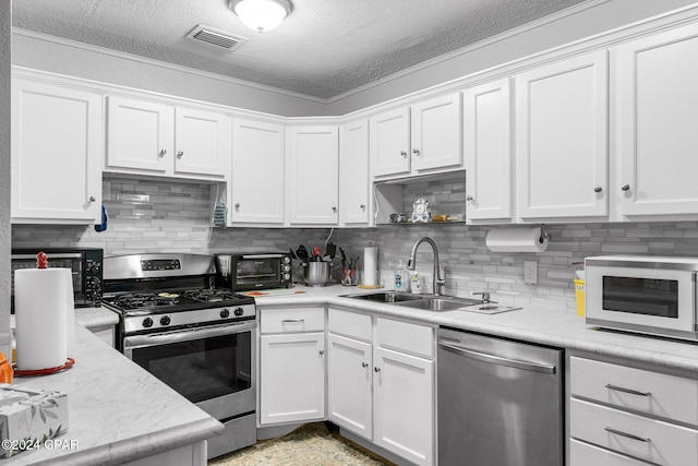 kitchen featuring appliances with stainless steel finishes, backsplash, a textured ceiling, sink, and white cabinetry