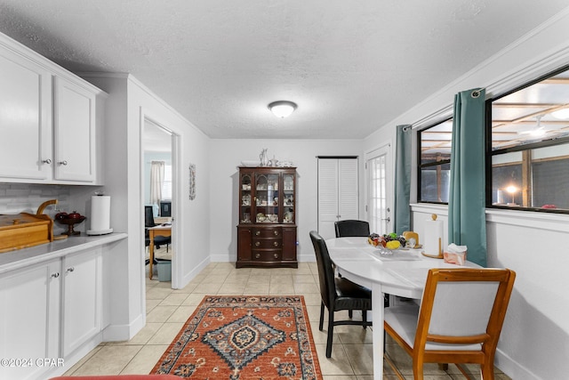 dining space with light tile patterned floors, a textured ceiling, a wealth of natural light, and ornamental molding