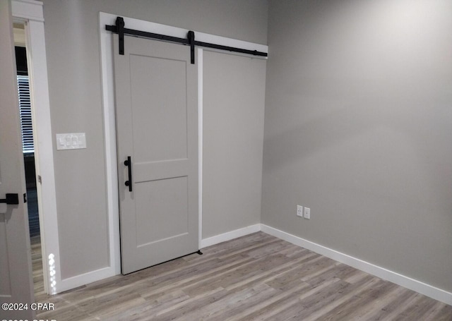 unfurnished room with a barn door and light wood-type flooring