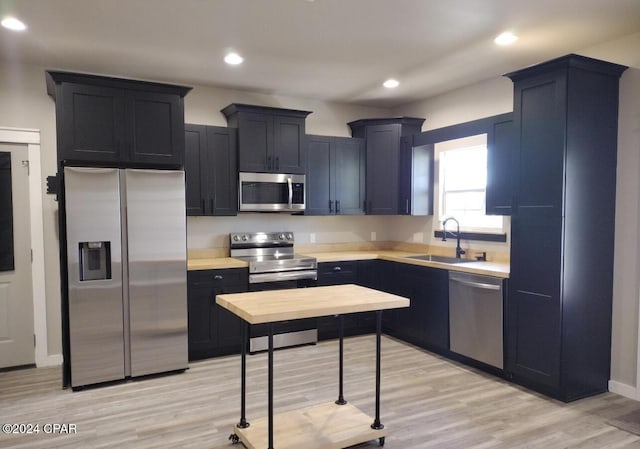 kitchen with stainless steel appliances, light hardwood / wood-style flooring, and sink