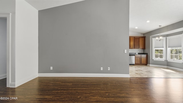 unfurnished living room with a chandelier, vaulted ceiling, and dark wood-type flooring