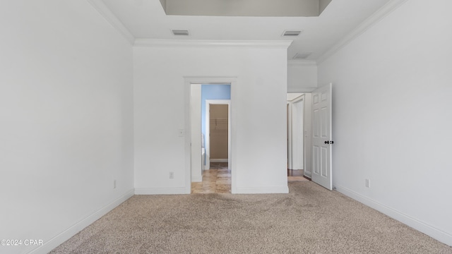 unfurnished bedroom with light carpet, a spacious closet, and crown molding