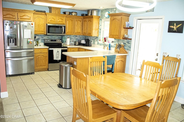 kitchen featuring kitchen peninsula, tasteful backsplash, stainless steel appliances, sink, and light tile patterned floors