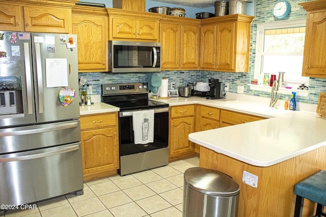 kitchen with decorative backsplash, light tile patterned floors, stainless steel appliances, and a breakfast bar