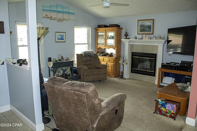 living room with a tiled fireplace, ceiling fan, light carpet, and lofted ceiling