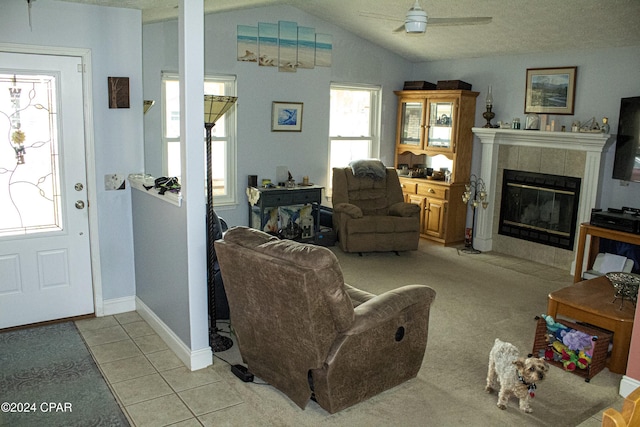 tiled living room with a tile fireplace, ceiling fan, and lofted ceiling