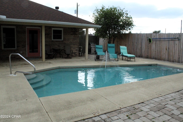 view of pool with a patio area and a grill