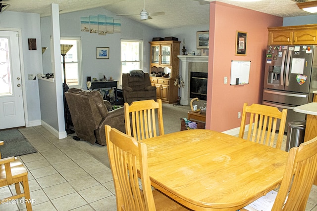 dining room featuring ceiling fan, light tile patterned floors, a textured ceiling, and lofted ceiling