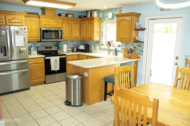 kitchen with kitchen peninsula, backsplash, stainless steel appliances, sink, and light tile patterned floors