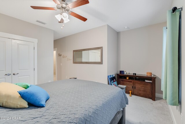 bedroom with ceiling fan, a closet, and light carpet