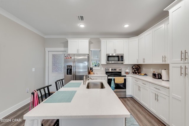 kitchen with a kitchen island with sink, sink, white cabinets, and appliances with stainless steel finishes