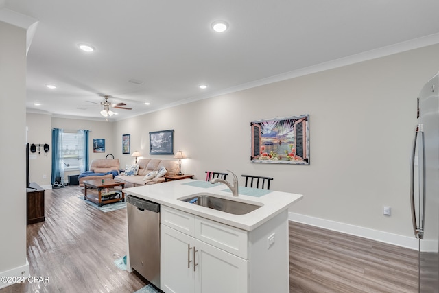 kitchen with sink, appliances with stainless steel finishes, ornamental molding, light hardwood / wood-style floors, and white cabinets