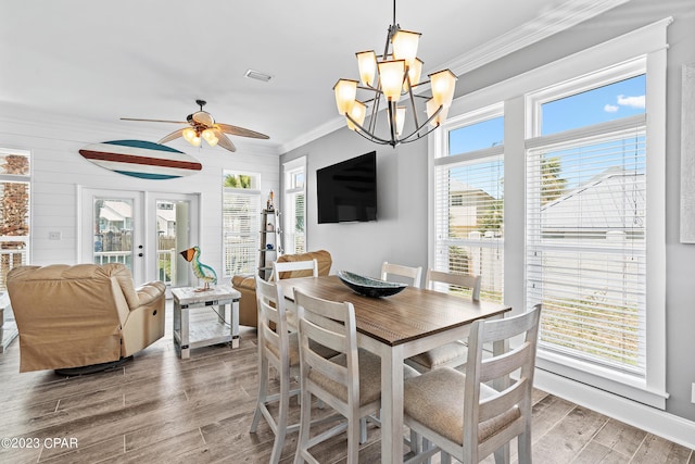 dining room with ceiling fan with notable chandelier, plenty of natural light, ornamental molding, and french doors