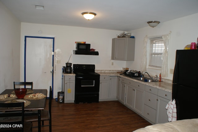 kitchen with light stone counters, gray cabinetry, dark wood-type flooring, sink, and black appliances