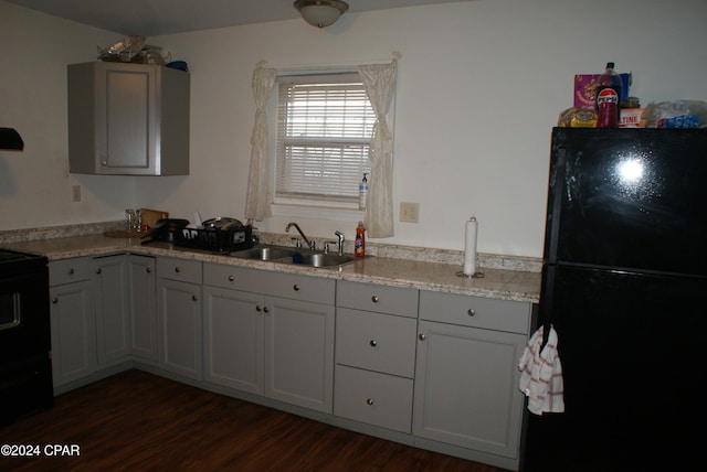 kitchen with black appliances, dark hardwood / wood-style floors, light stone counters, and sink