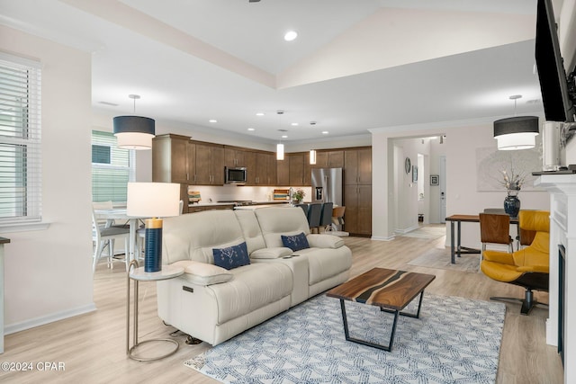 living room with lofted ceiling, ornamental molding, plenty of natural light, and light hardwood / wood-style flooring