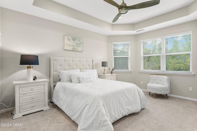 carpeted bedroom featuring ceiling fan and a raised ceiling