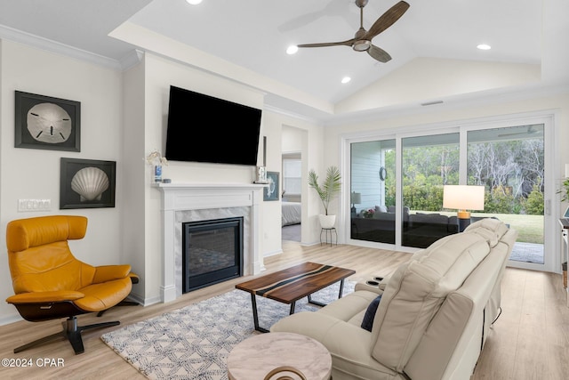 living room with light wood-type flooring, crown molding, ceiling fan, a fireplace, and lofted ceiling