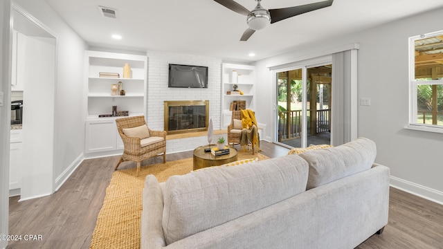 living room with hardwood / wood-style floors, a brick fireplace, plenty of natural light, and ceiling fan