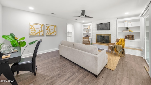 living room with a fireplace, hardwood / wood-style floors, ceiling fan, and built in shelves