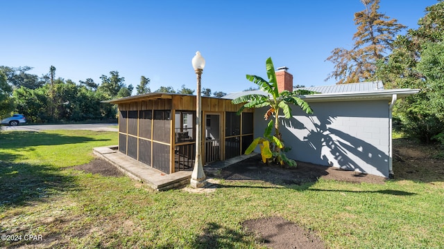 view of outbuilding with a sunroom and a lawn