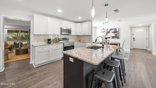 kitchen with sink, dark wood-type flooring, stainless steel appliances, decorative light fixtures, and white cabinets