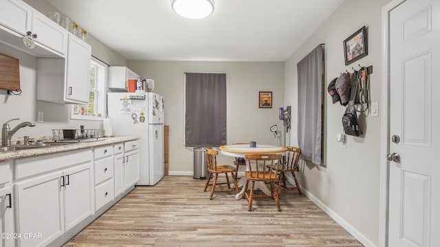 kitchen featuring white fridge, white cabinetry, light hardwood / wood-style floors, and sink