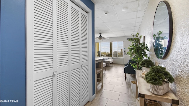 corridor featuring a paneled ceiling and light tile patterned flooring