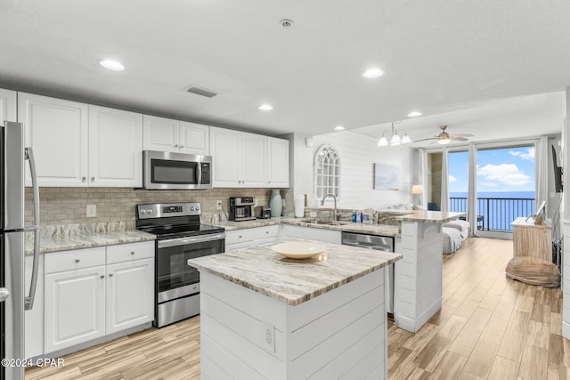 kitchen featuring white cabinets, light wood-type flooring, a center island, and stainless steel appliances