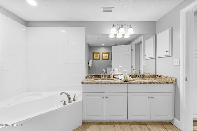 bathroom featuring vanity, wood-type flooring, a textured ceiling, and a bathing tub