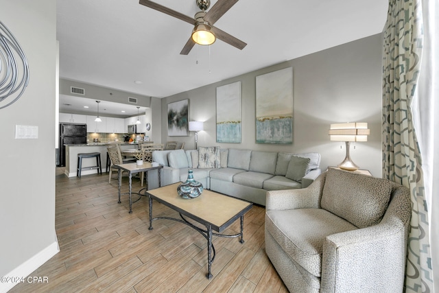 living room featuring ceiling fan and light hardwood / wood-style floors