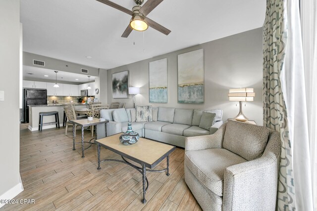 living room with light wood-type flooring and ceiling fan