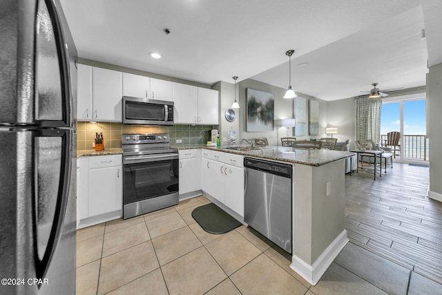 kitchen featuring white cabinetry, ceiling fan, stainless steel appliances, kitchen peninsula, and decorative light fixtures