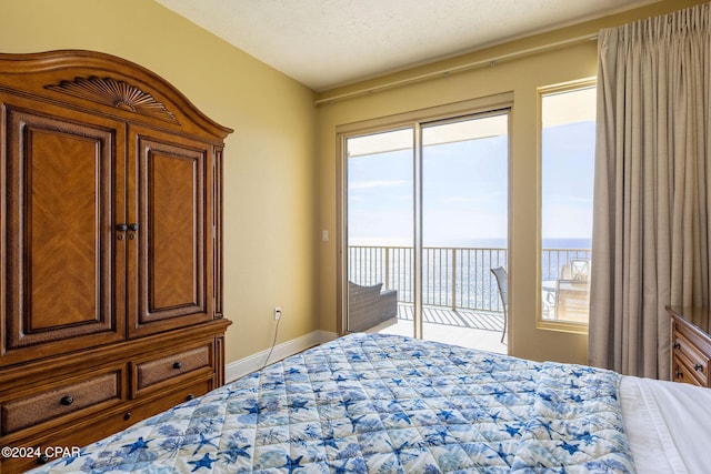 bedroom featuring a water view, access to exterior, and a textured ceiling