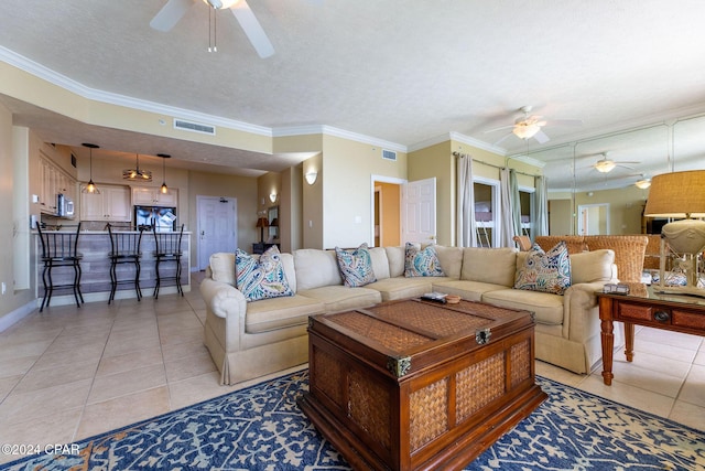 living room with light tile patterned floors, ornamental molding, a textured ceiling, and ceiling fan